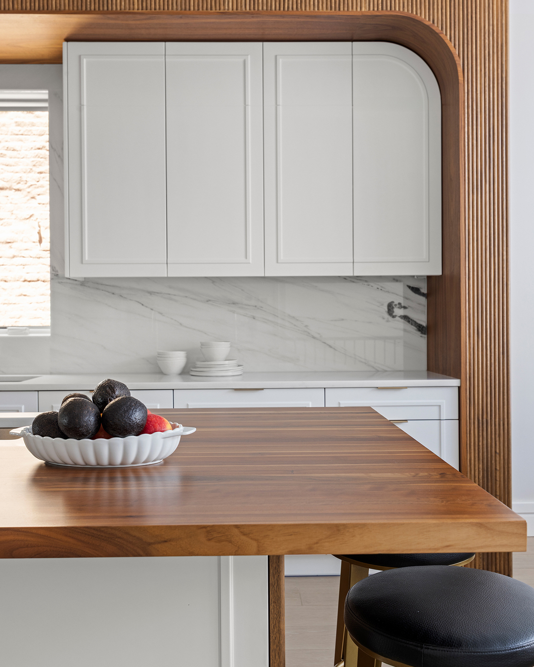 A kitchen featuring a wooden countertop with matching stools arranged around it.